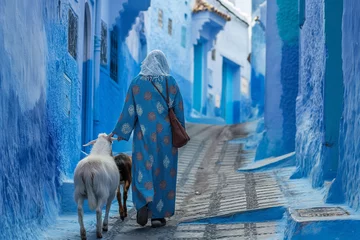 Fotobehang  shepherd women with their goats, walking down the blue-white streets in Chefchaouen - the blue city Morocco - amazing palette of blue and white buildings © Natalia Schuchardt