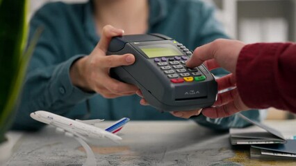 Tickets, an office worker provides a payment terminal for online card payment in an office space, concept of a young woman conducting a customer check-in, helping with paperwork, embassy