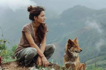 Fotobehang woman and dog sit on the mountainside and look into the distance © SERGEY