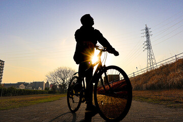 Silhouette man on a bike with head looking up with beautiful sunset.