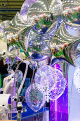A room with a large number of shiny silver foil balloons, some near the ceiling, others closer to the floor. Balloons emphasize the festive atmosphere.