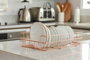 A kitchen scene showing a set of clean dishes neatly placed in a rose gold dish rack next to a kitchen sink. In the background, there is a toaster and some kitchen utensils, creating a scene o - obrazy, fototapety, plakaty