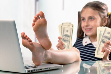 Cheerful young happy business girl counts profits, took off her shoes and working in office with...