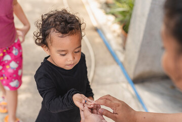 Woman in casual wear giving a sweet treat to a child outdoors