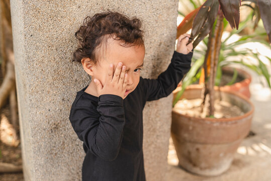 Young Asian toddler feeling upset after being scolded, holding face with hand