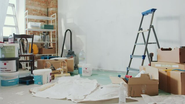Interior of living room with boxes, paint buckets, tools and ladder during home improvement. No people, daytime