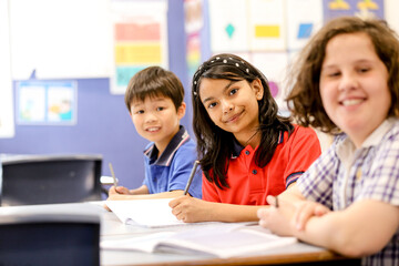 Public school students sitting at their desk smiling