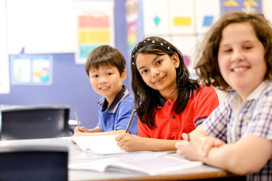 Public school students sitting at their desk smiling