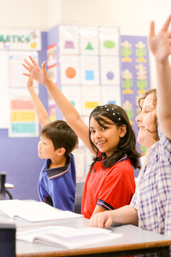 Happy students in the classroom wanting to answer a question