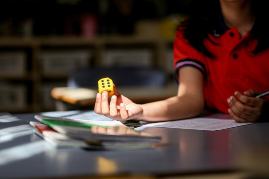 girl student at her desk working on maths problems using dice