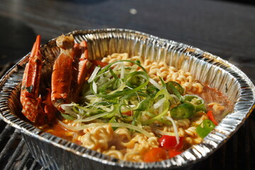 Instant ramen boiled in an aluminum disposable container with seafood such as crab