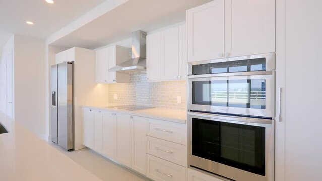 Scandinavian luxurious kitchen in new splendid apartment with integrated contemporary technology and comfortable granite island. Bright design with white cabinets and shelves