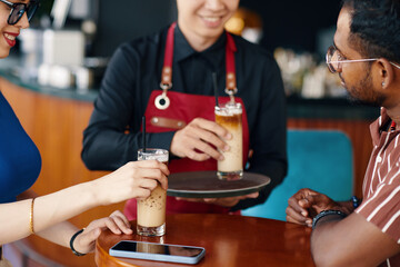 Cheerful couple ordered iced coffee in coffeeshop