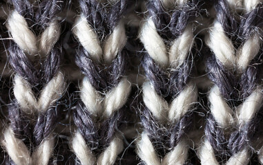 Close-up of hand-knit striped wool fabric with voluminous braids. Natural gray and white wool textile background. Warm woolen cozy clothes. Flat lay, macro, top view, mockup