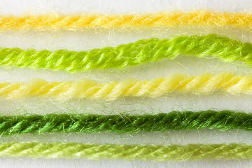 Spring needlework concept. Close-up view of green and yellow hand knitting yarn on white background. Woolen, acrilic, cotton and blended yarn for spring-summer season. DIY concept. Macro, flat lay
