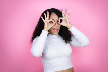 African american woman wearing casual sweater over pink background doing ok gesture shocked with...