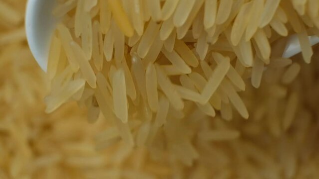 Long grain parboiled basmati rice pouring with spoon macro slow motion