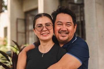 Happy middle-aged Asian couple embracing in casual attire