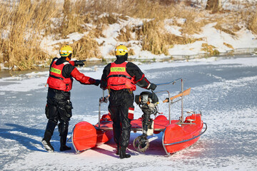 Ratownik wodny w zimie na lodzie ratuje topielca.  - obrazy, fototapety, plakaty