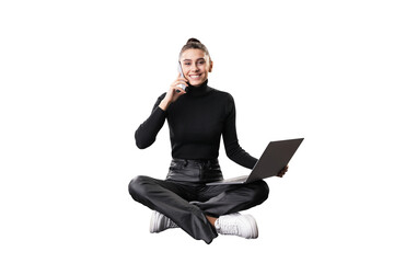 A young woman sits cross-legged, holding a laptop and talking on the phone, isolated on a white...