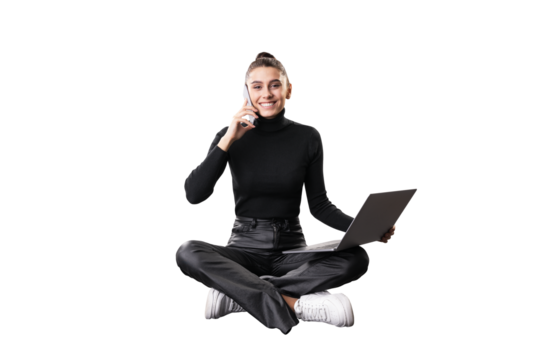 A young woman sits cross-legged, holding a laptop and talking on the phone, isolated on a white background, embodying a multitasking business concept