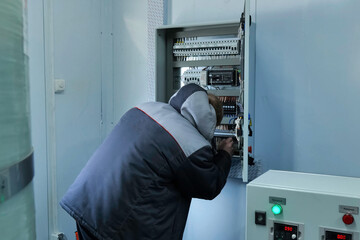 worker repairs equipment in a relay electrical cabinet.