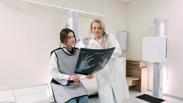A male medical doctor discusses the results of an X-ray image with a young female patient. Concept of medical technologies, treatment and health status.