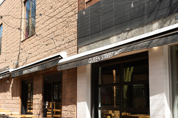 Fototapeta premium patio area awnings with sign of Queen Street Warehouse, a restaurant, located at 232 Queen Street West in Toronto, Canada