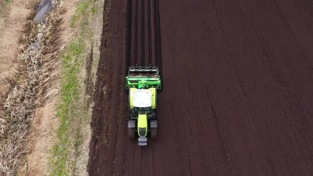 Farmer seeding crops at field. Farmer with a tractor on the agricultural field sowing.