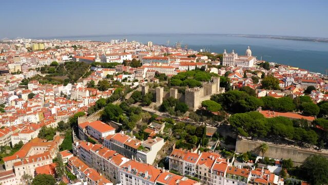 Aerial Forward Shot Of Famous Castelo De S Jorge In Residential City By Tagus River On Sunny Day - Lisbon, Portugal