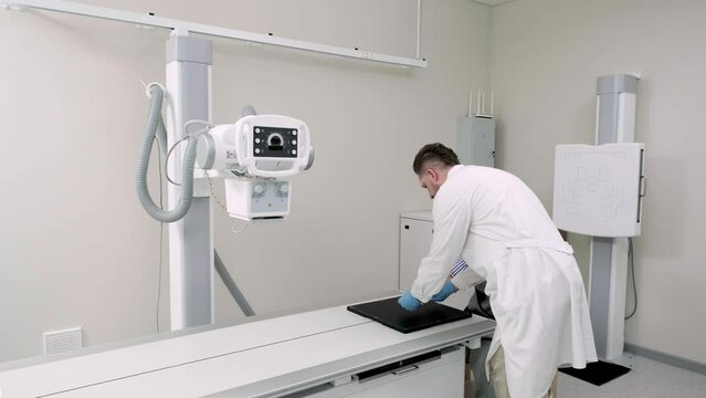 A patient in the x-ray room takes a picture of his arm. Concept of health, treatment and modern medical technologies.