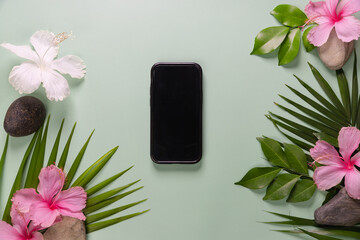Smartphone with spring flowers on green background. 