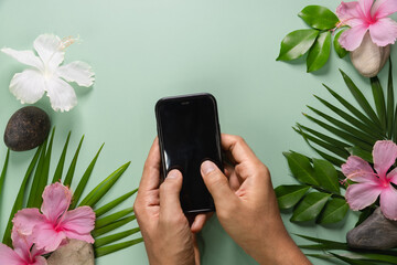 Smartphone with spring flowers on green background. 