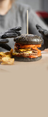 Fast food, people and unhealthy eating concept. woman hands in gloves holding black hamburger or burger sitting in restaurant. Copy space