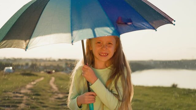 Girl stands rotating umbrella under rain