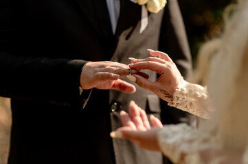 The bride puts a wedding ring on the groom's finger	