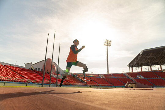 Asian para-athlete runner prosthetic leg on the track alone outside on a stadium track Paralympic running concept.