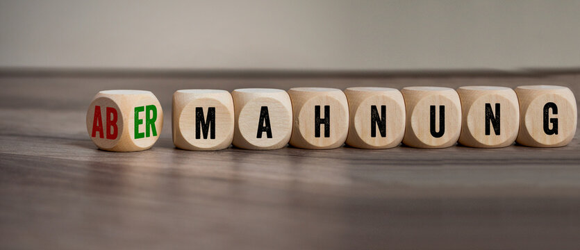 Cubes, dice or blocks with the german words for warning and admonition - abmahnung und ermahnung on wooden background