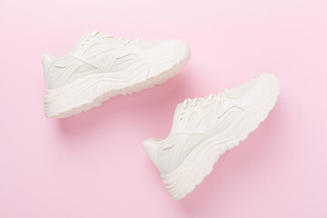 White woman trendy sneakers on color background, top view