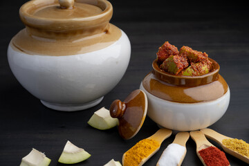 Homemade Mango Pickle or aam ka achar Kairi Loncha stored or preserved in China clay pot with Ingredients. - obrazy, fototapety, plakaty