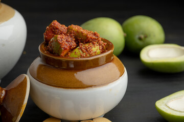 Homemade Mango Pickle or aam ka achar Kairi Loncha stored or preserved in China clay pot with Ingredients.
