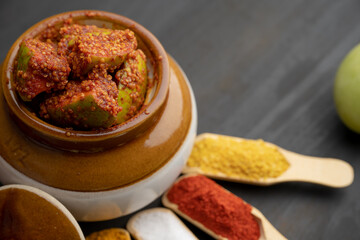 Homemade Mango Pickle or aam ka achar Kairi Loncha stored or preserved in China clay pot with Ingredients.