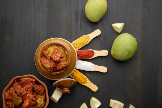 Homemade Mango Pickle or aam ka achar Kairi Loncha stored or preserved in China clay pot with Ingredients.