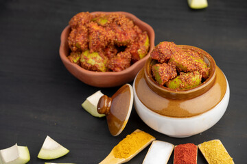 Homemade Mango Pickle or aam ka achar Kairi Loncha stored or preserved in China clay pot with Ingredients.