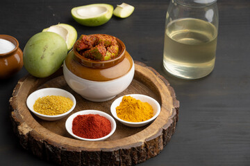 Homemade Mango Pickle or aam ka achar Kairi Loncha stored or preserved in China clay pot with Ingredients.