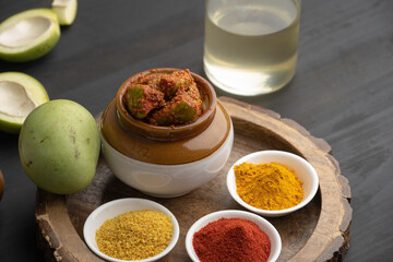 Homemade Mango Pickle or aam ka achar Kairi Loncha stored or preserved in China clay pot with Ingredients.