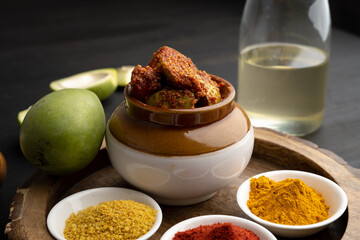 Homemade Mango Pickle or aam ka achar Kairi Loncha stored or preserved in China clay pot with Ingredients.