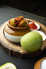 Homemade Mango Pickle or aam ka achar Kairi Loncha stored or preserved in China clay pot with...