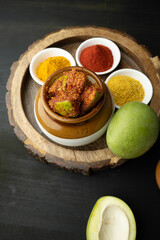 Homemade Mango Pickle or aam ka achar Kairi Loncha stored or preserved in China clay pot with Ingredients.