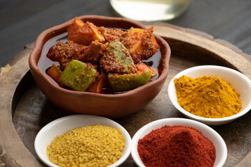 Homemade Mango Pickle or aam ka achar Kairi Loncha stored or preserved in China clay pot with Ingredients.